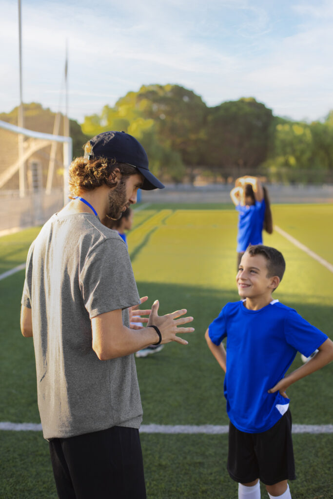entrenador-de-futbol-de-vista-lateral-ayudando-los-ninos